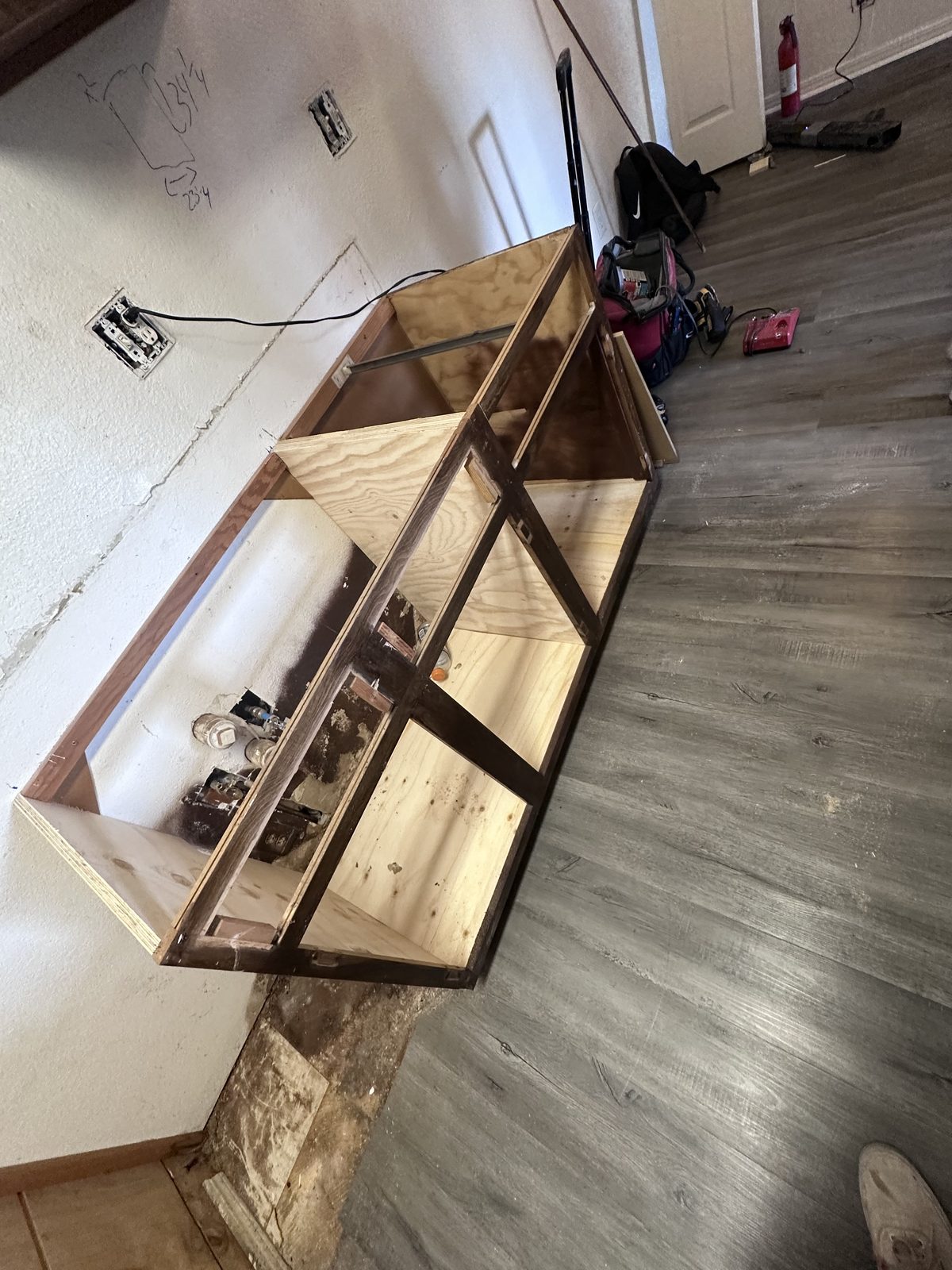 Custom built wooden cabinet with glass doors standing in a sunlit room with dark wood flooring